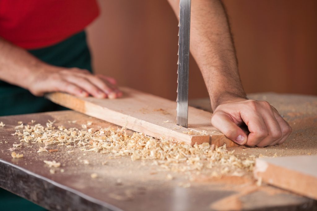 a person uses a bandsaw to cut a piece of wood